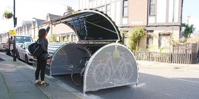 Woman closing the lid for a bikehangar on a residential street