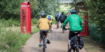 Group cycling through a forest between some red telephone boxes