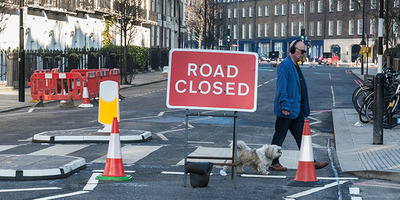 Road works signage and person walking across the road