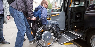 Man boarding taxi using wheelchair ramp