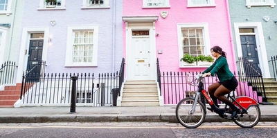 woman cycling along colourful houses