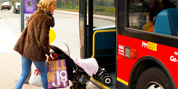 Woman boarding a bus with a buggy