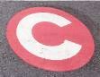 road marking with a red circle and white letter 'C' inside